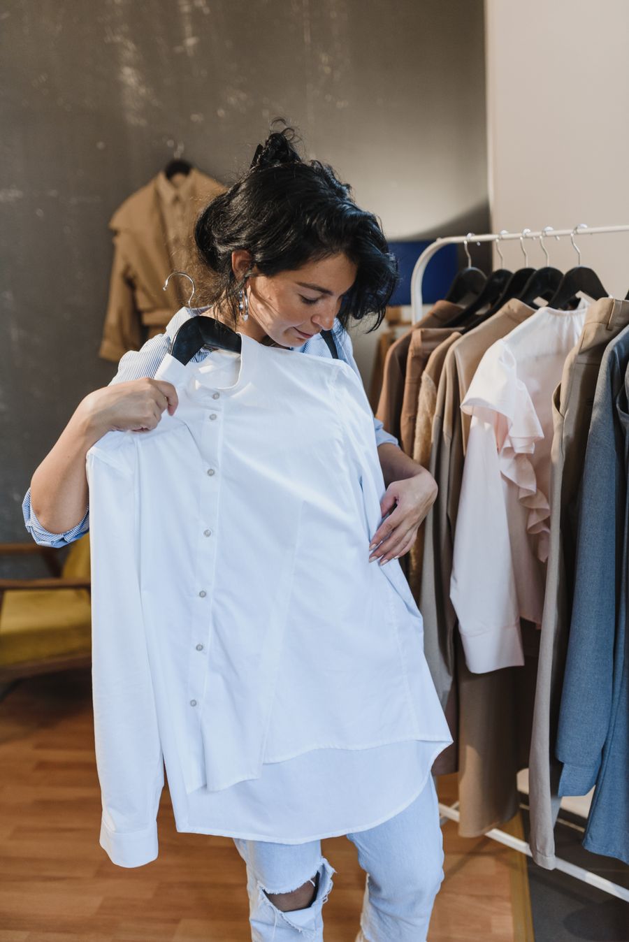 Mulher na loja segurando uma camisa contra o corpo